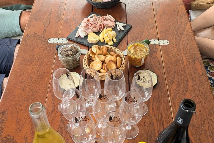People seated around a table with snacks, wine glasses, and bottled drinks.