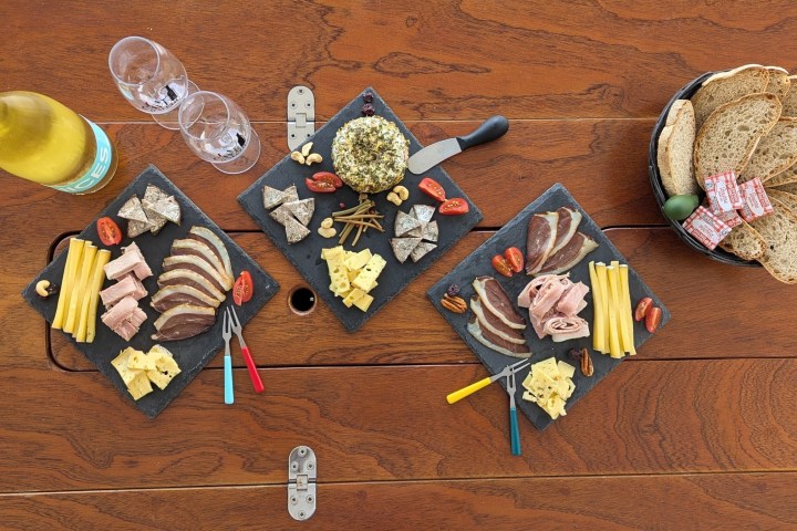 Charcuterie boards with cheese, meats, bread, and wine on a wooden table.