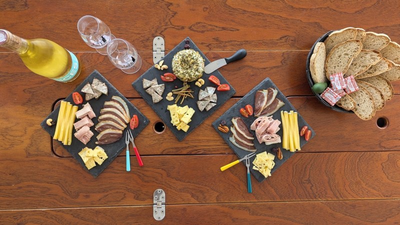 Charcuterie boards with cheese, meats, bread, and wine on a wooden table.
