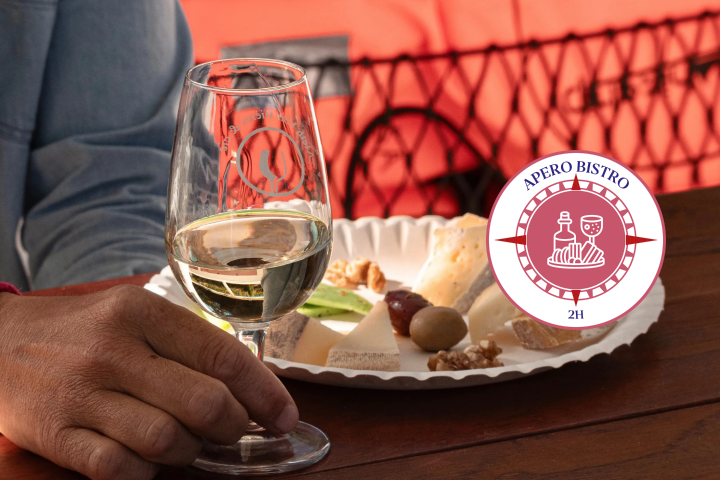 Person holding wine glass with cheese plate and bistro logo.