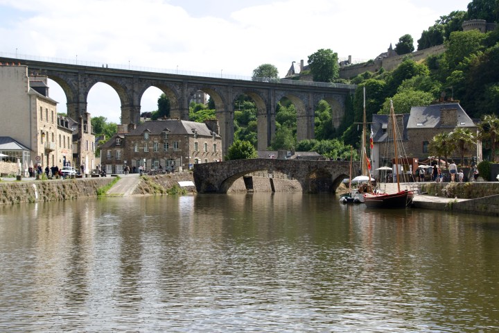 Stone bridge over calm river, with arches and surrounding historic buildings.